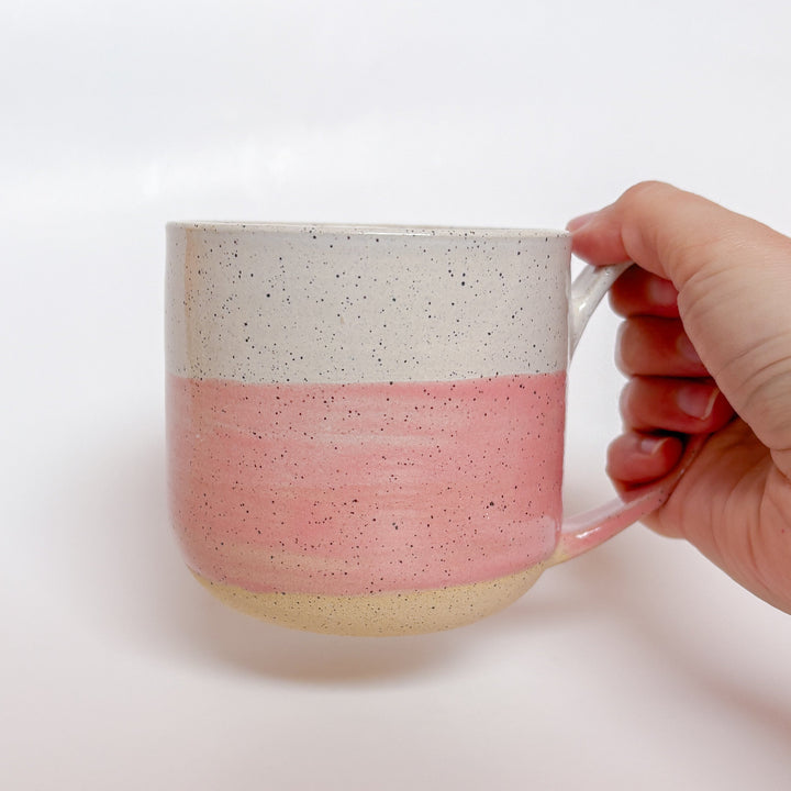Valerie Daoust Ceramics Pink Dipped Mug, a handmade ceramic mug with a colorblock design featuring a light gray top and a speckled pink middle section, displayed on a light gray background. The mug has a large, rounded handle, a speckled texture, and is made in Mississippi Mills, Ontario, Canada.