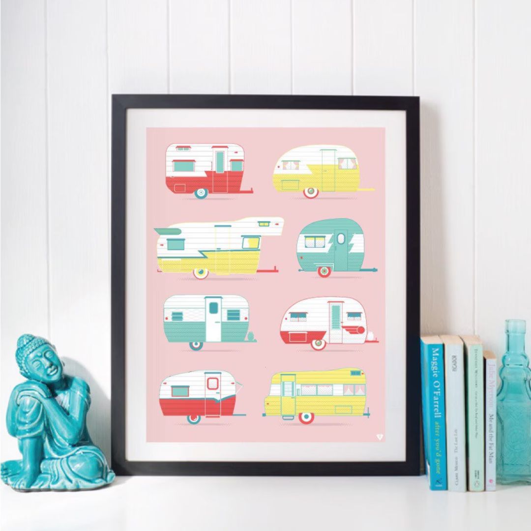 Framed artwork with colorful vintage camper illustrations on a pink background, displayed on a white surface.