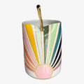 Colorful striped mug with a gold straw on a white background