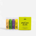 A set of four Epic Blend vegan lip balms in a yellow box. The lip balms are in different colors and flavors: peach, pineapple mint, wild berry, and coconut lemon. The box has the text "Plant One On Me" and "Vegan Lip Balms" written on it.