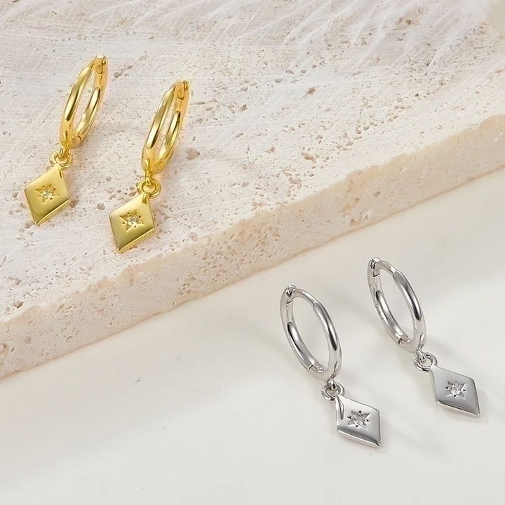 diamond drop earrings featuring small gold hoops with dangling rhombus-shaped charms, each with a central sparkling crystal resembling a North Star. These elegant earrings are available in Ottawa, Ontario, Canada.