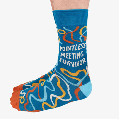 A pair of blue crew socks featuring a colourful confetti-like pattern in shades of orange, yellow, and white. One sock displays the text 