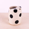 Ceramic mug with black polka dots on a light pink background
