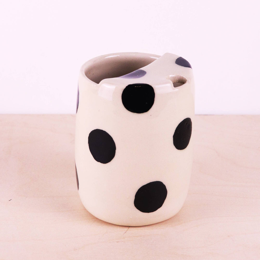 Ceramic mug with black polka dots on a light pink background