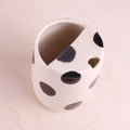 White ceramic planter with black polka dots on a beige background