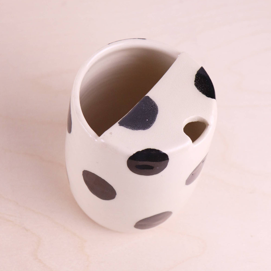 White ceramic planter with black polka dots on a beige background
