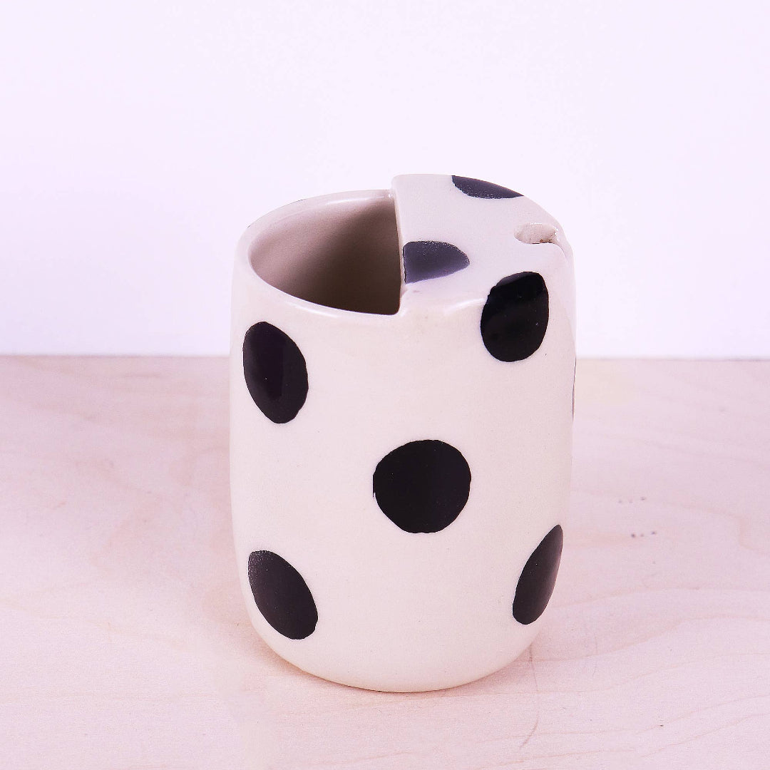 Ceramic mug with black polka dots on a light pink background