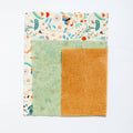 Fabric square with floral border, green patch, and orange patch on a white background