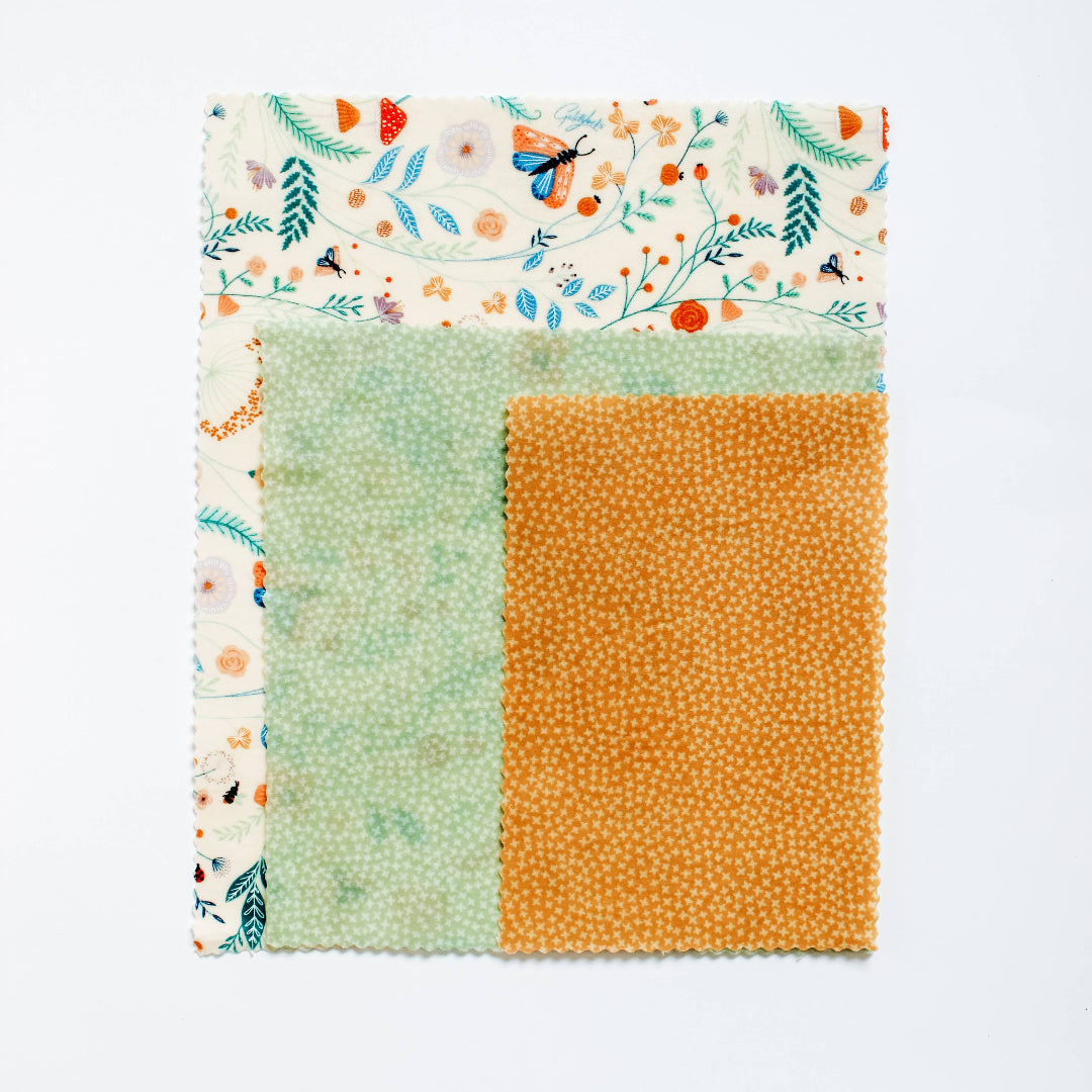 Fabric square with floral border, green patch, and orange patch on a white background