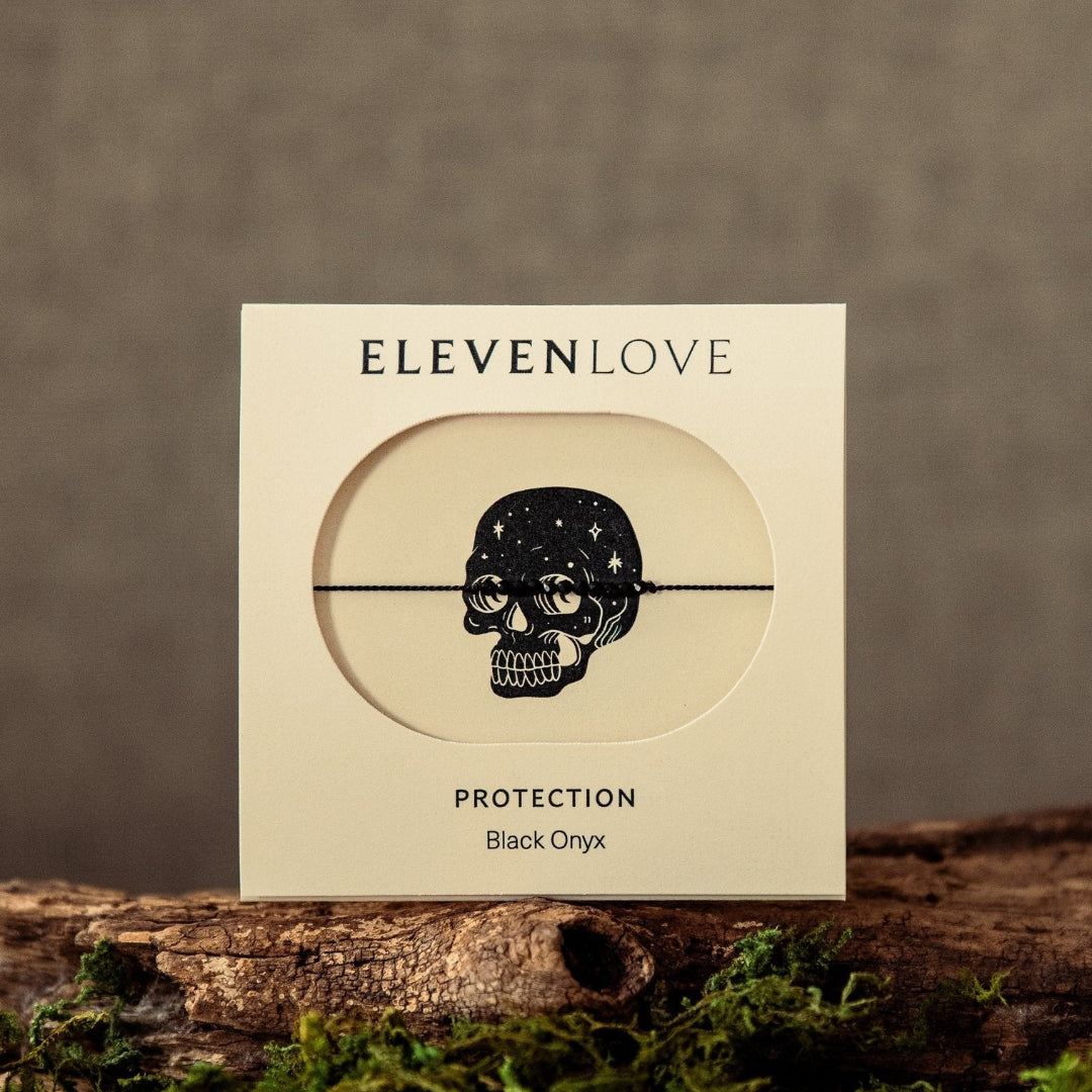 Product packaging for 'Protection' by Eleven Love on a wooden surface with moss, against a brown background.