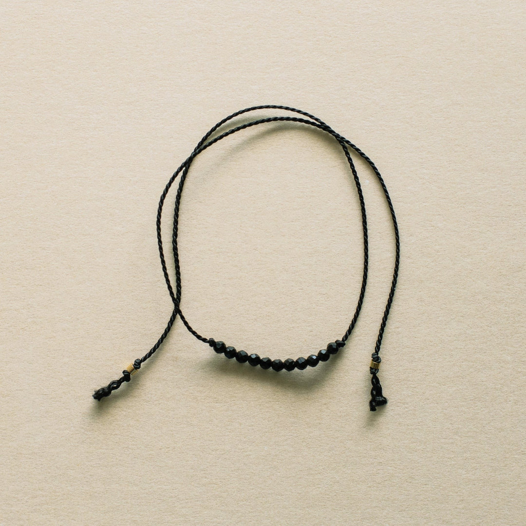 Black beaded necklace on a beige background