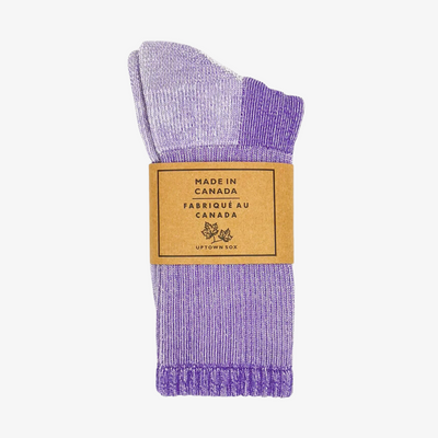 A pair of purple socks rolled up and packaged with a label that reads 