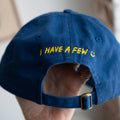 Blue cap with yellow text held by a hand against a blurred background
