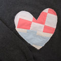 a grey sweatshirt with a large, heart-shaped patch. The patch is made from various fabrics with various patterns, sewn together in a patchwork style.