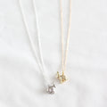 Two gold and silver cat-shaped pendants on thin chains against a white background.
