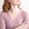 Woman wearing a gold necklace with a heart pendant against a white background