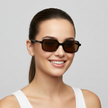 Woman wearing dark sunglasses against a light gray background