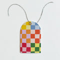 A package of 8 gift tags and twine. The tags feature a colorful checkered pattern in pink, yellow, blue, and green. The packaging is white with the Idlewild Co. logo and information about the product.