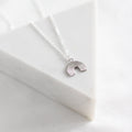 Silver rainbow necklace on a white fabric background
