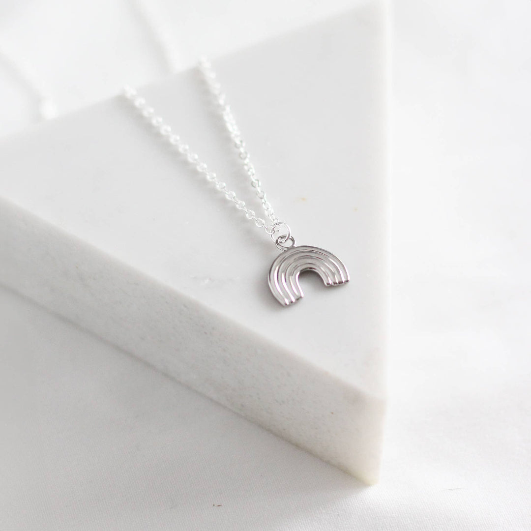 Silver rainbow necklace on a white fabric background