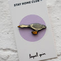 Stay Home Club lapel pin on a card with a goose design against a light gray background