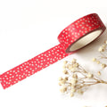 Red washi tape with white polka dots on a white background with dried flowers.