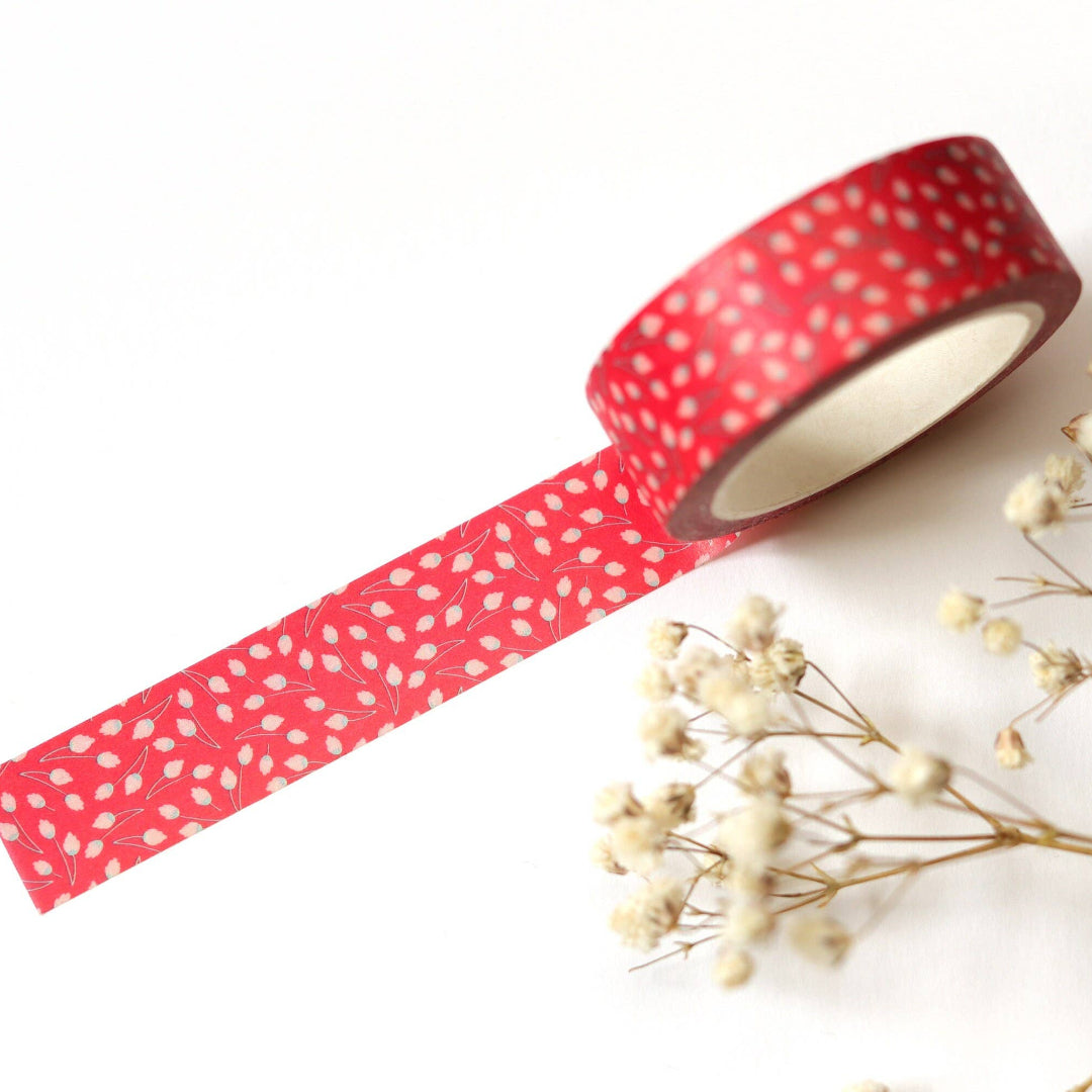 Red washi tape with white polka dots on a white background with dried flowers.