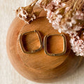 Gold hoop earrings on a wooden surface with pink flowers