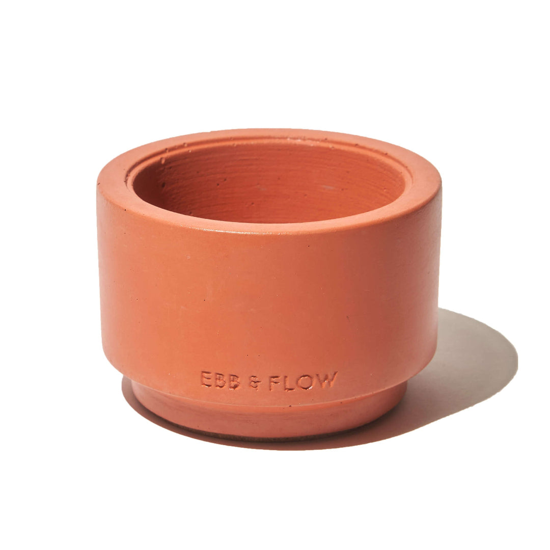 Terracotta-colored planter with 'Ebb & Flow' branding on a white background