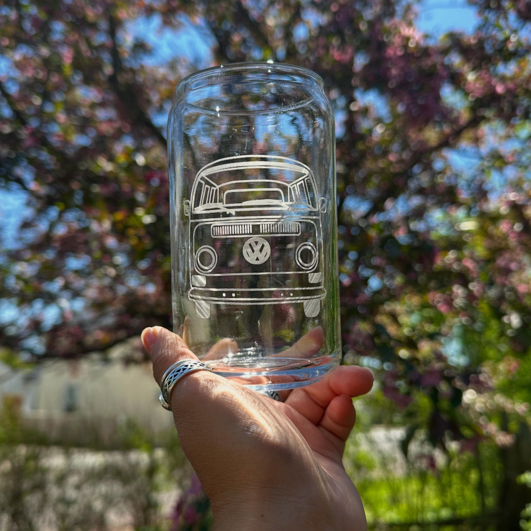 Clear glass with a Volkswagen van etching held in front of a blurred outdoor background with trees.