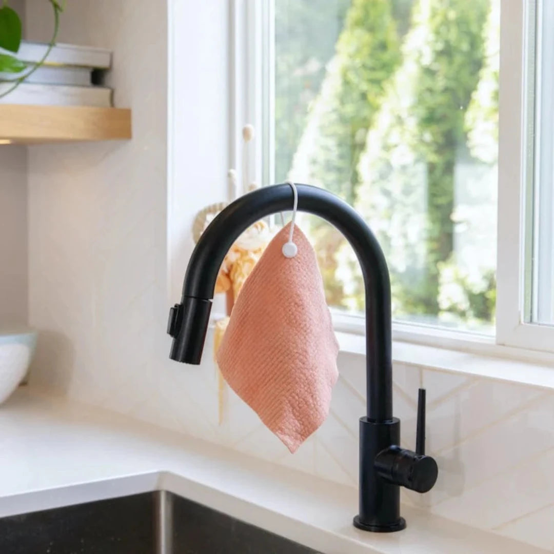 A coral-colored Swedish dishcloth. The dishcloth has a textured surface and is labeled "Goldilocks Swedish Dishcloth" with information about its compostability, reusability, and machine washability.