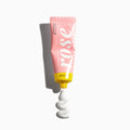 Pink tube of cream with white swirl on a white background