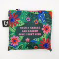 A green tote bag with a floral pattern. The text "Mostly Snacks and Random Junk I Don't Need" is printed on the bag.