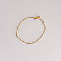 Gold bracelet on a light gray background