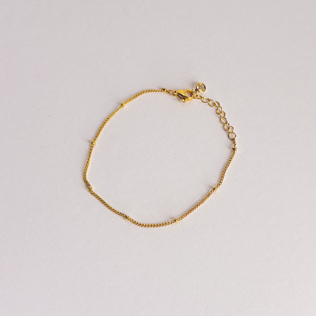 Gold bracelet on a light gray background
