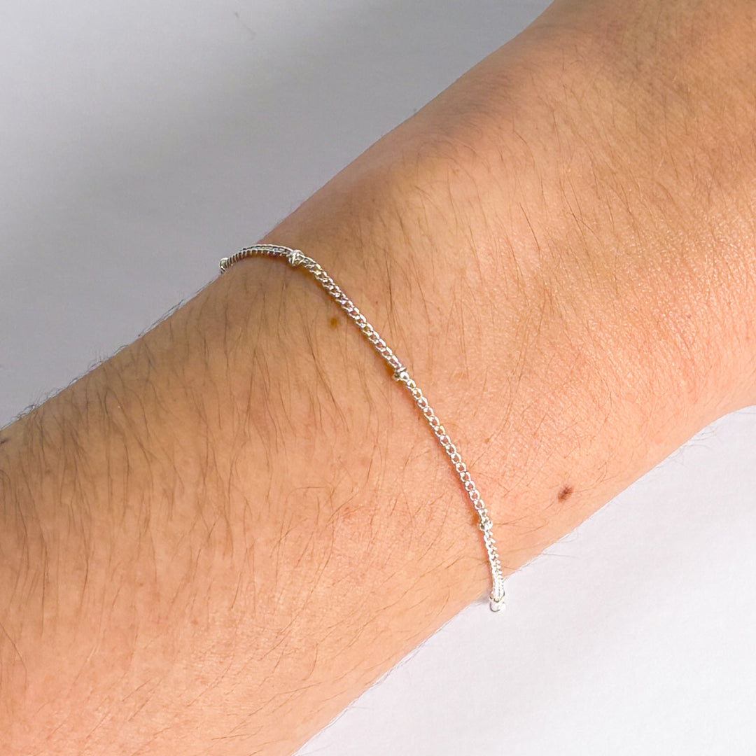 Silver bracelet on a person's wrist with a plain background