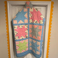 A long patchwork jacket made from pastel Sawtooth Star quilt blocks with a high collar and metal snaps, hanging on a white door framed by a yellow scalloped border.

If you’d like a more whimsical, minimalist, or fashion‑forward tone, I can shape the description however you like.