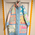 A long patchwork jacket made from pastel Sawtooth Star quilt blocks with a high collar and metal snaps, hanging on a white door framed by a yellow scalloped border.

If you’d like a more whimsical, minimalist, or fashion‑forward tone, I can shape the description however you like.