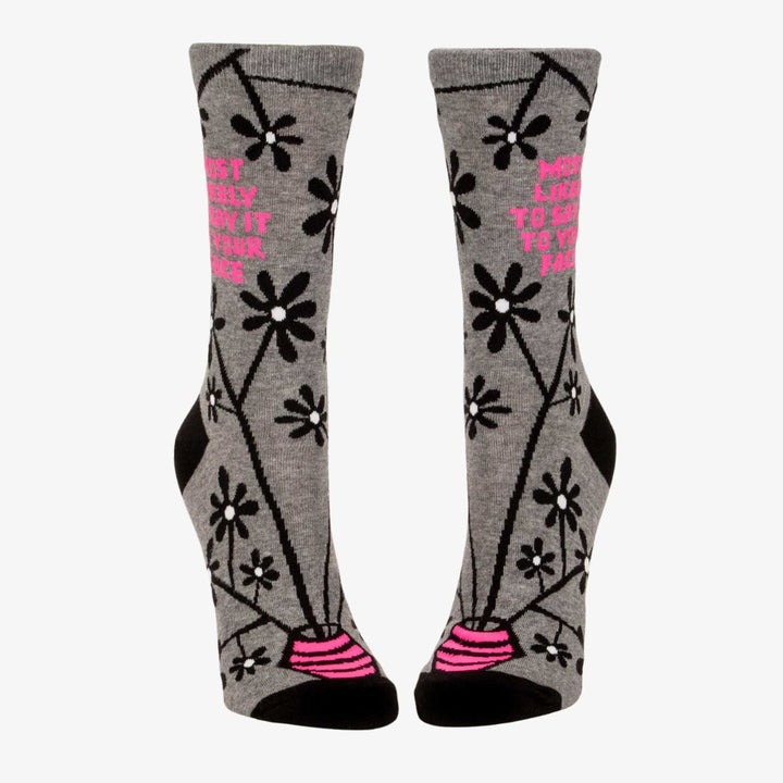 A pair of women's crew socks with a grey background and a pattern of black and white flowers on branches. One sock has text in bright pink that reads 