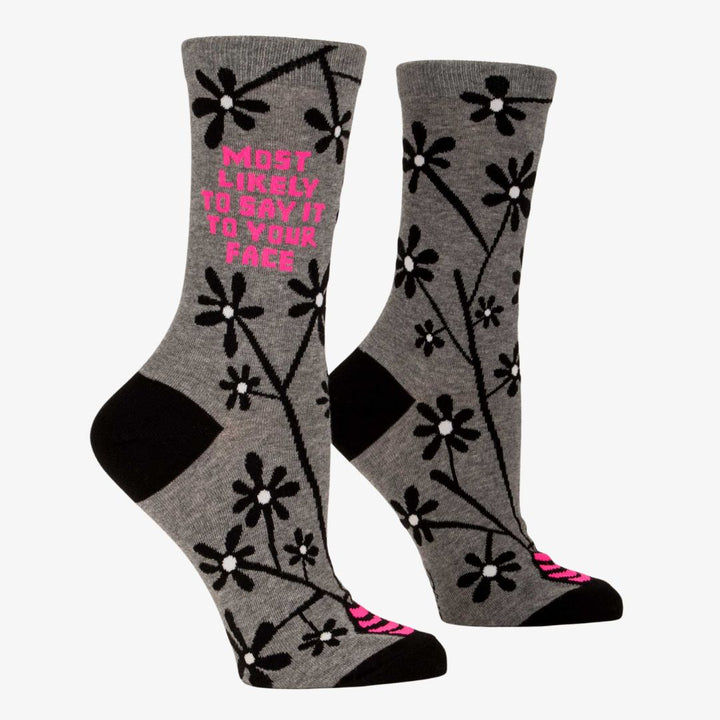 A pair of women's crew socks with a grey background and a pattern of black and white flowers on branches. One sock has text in bright pink that reads 