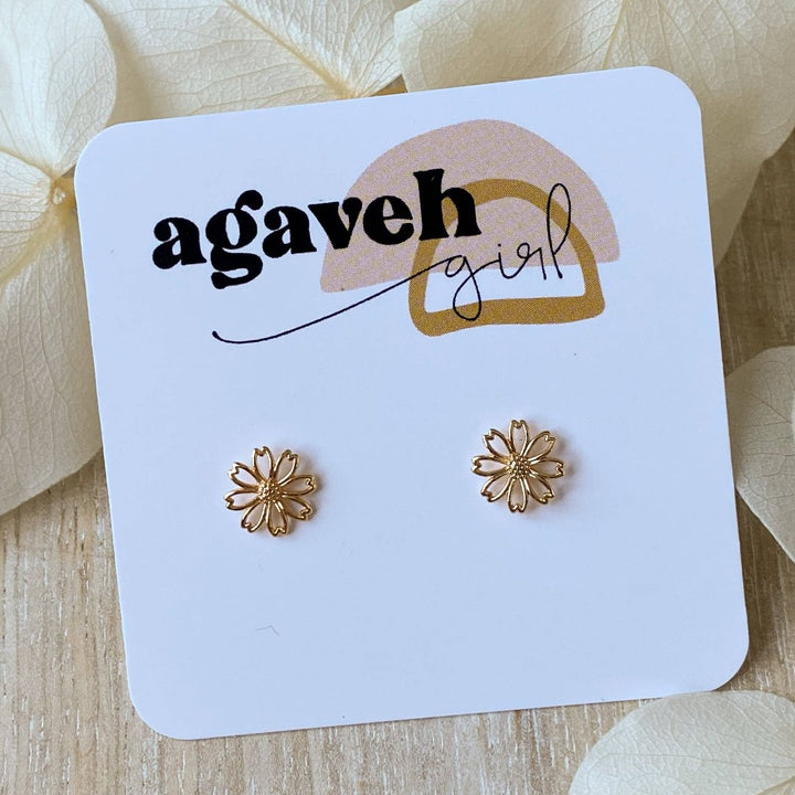 A pair of gold daisy stud earrings on a white background. The earrings have a delicate, openwork design with a small circle in the center of each flower.