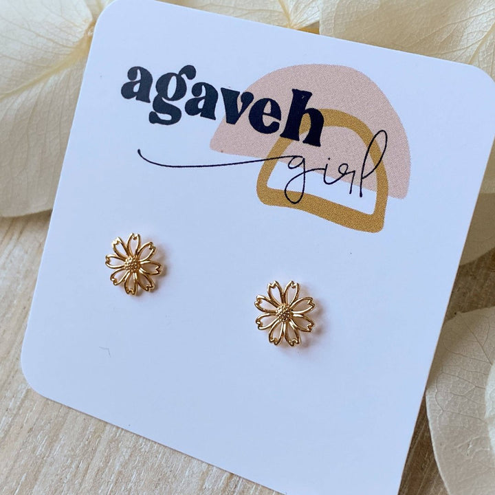 A pair of gold daisy stud earrings on a white background. The earrings have a delicate, openwork design with a small circle in the center of each flower.