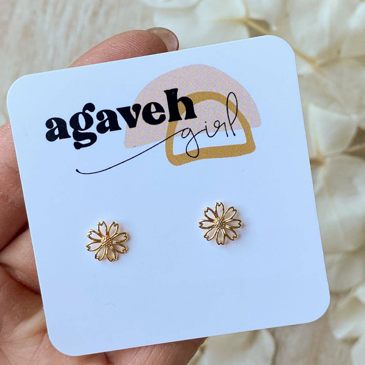 A pair of gold daisy stud earrings on a white background. The earrings have a delicate, openwork design with a small circle in the center of each flower.