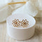 A pair of gold daisy stud earrings on a white background. The earrings have a delicate, openwork design with a small circle in the center of each flower.