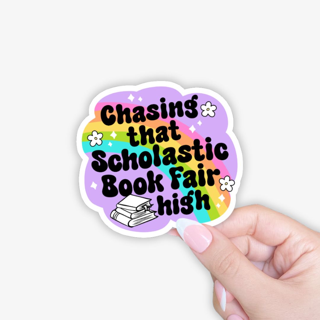 Sticker with 'Chasing that Scholastic Book Fair high' text on a colorful background held by a hand.