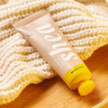 Skincare product with yellow cap on a textured surface