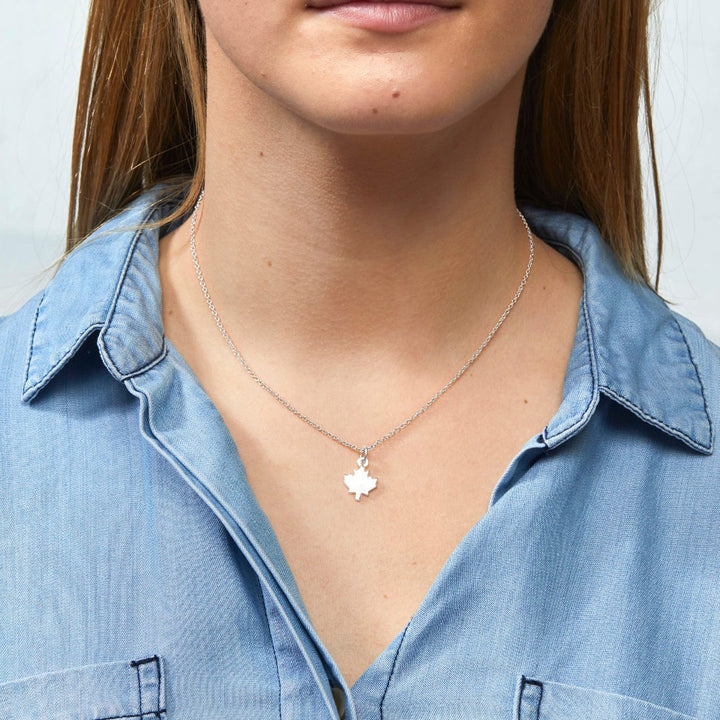 A silver necklace with a maple leaf pendant.