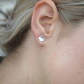 A pair of silver maple leaf stud earrings.