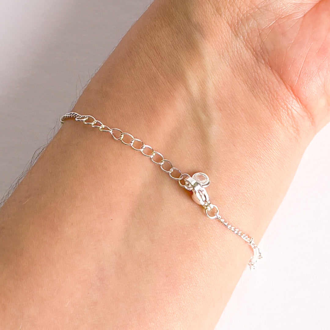 Silver chain bracelet on a wrist with a plain background