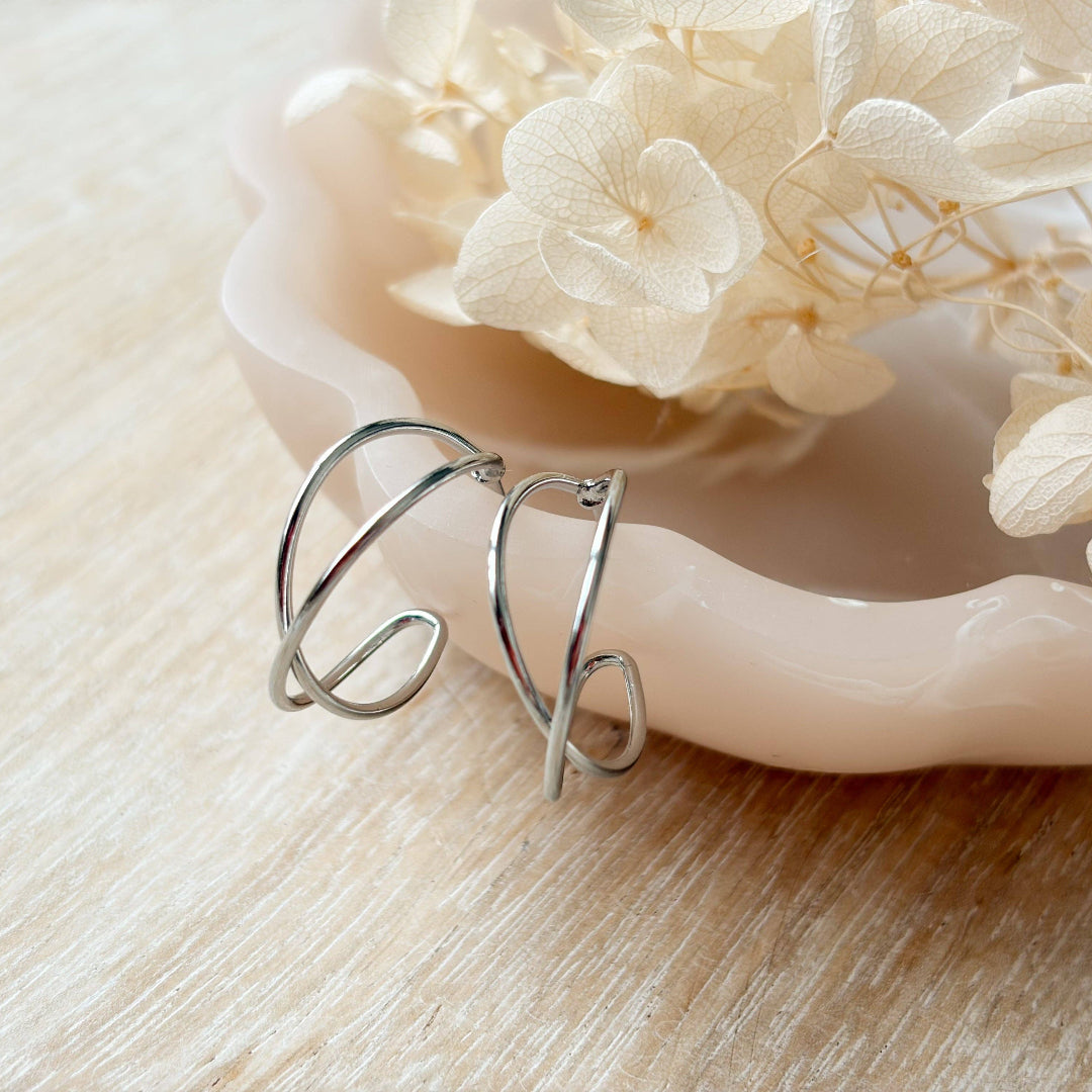 Silver ring with a unique design on a wooden surface with white flowers.